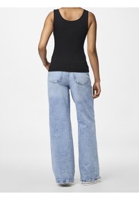 Svart ribbad linne topp, kombinerad med ljusblå vida jeans som har rak passform, fem fickor och subtila blekningar.