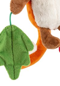 Plush toy with orange body, white chest, brown limbs, and a green leaf attached. Soft texture and detailed facial features visible.