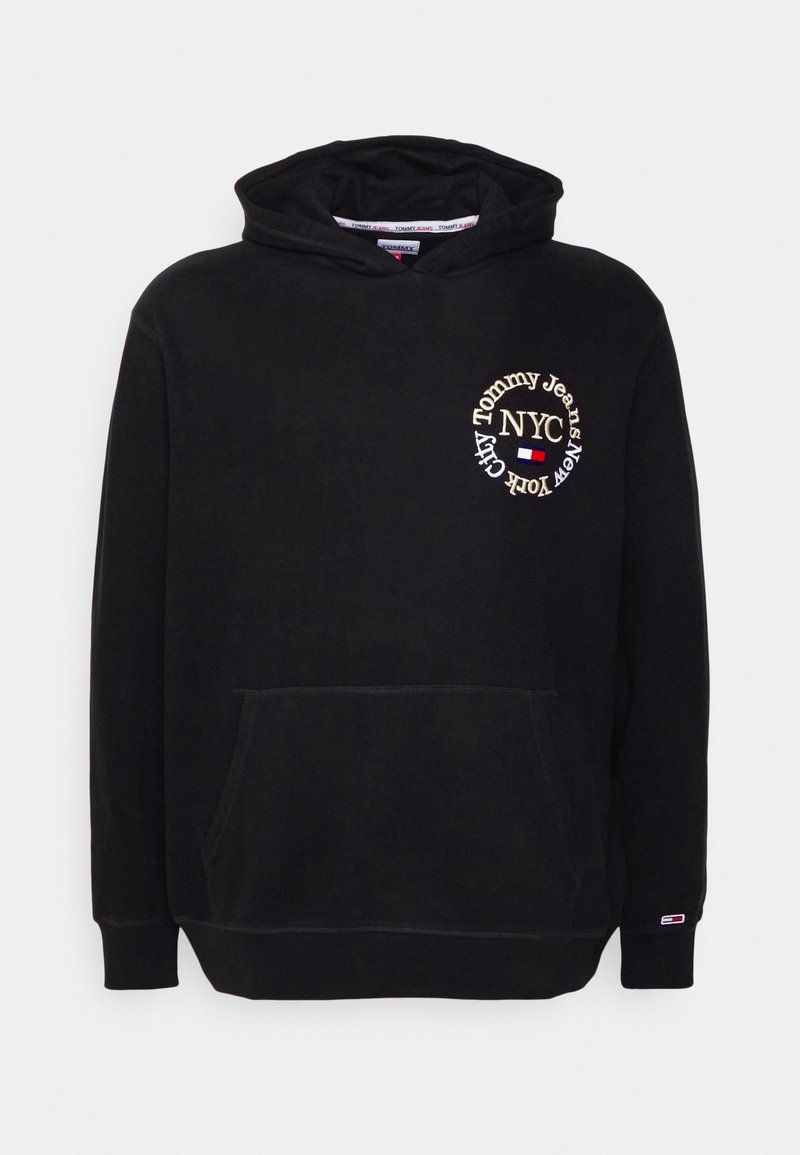 Hoodie noir avec une poche avant, arborant un logo circulaire brodé "Tommy Jeans NYC" en or. Tissu doux et texturé.