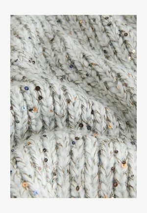 Tykt striktrøje stof i lysegrå med metalliske pailletter og strukturerede, chunky fletninger. Blød, fuzzy tekstur med dekorative detaljer.