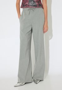 Grijs gestreepte wijde pantalons met een trekkoord in de taille, met een lichtblauwe accent aan de zijkant, gemaakt van een zachte, gladde stof.