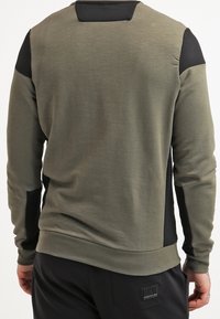 Olijfgroen sweatshirt met lange mouwen, geribbelde schouderaccenten en zwarte, gestructureerde zijpanelen. Glad stof met een fitted ontwerp.