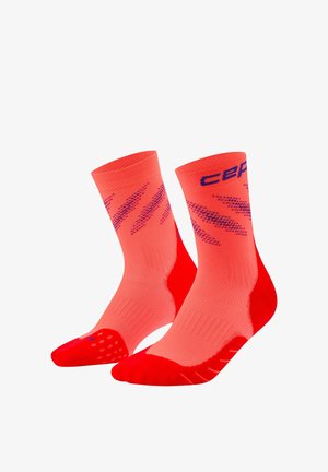 Pair of bright red and coral athletic socks with purple diagonal patterns and text on the upper cuffs.