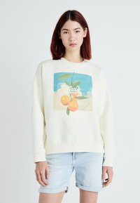 Krém színű pulóver, narancsok és levelek grafikájával egy kék ég háttér előtt, középen a "Levi's" felirattal.