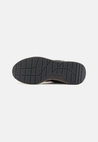 Crna gumena potplat s dubokim uzorkom. Sadrži urezani "Levi's" logo blizu pete. Glatka, izdržljiva tekstura.
