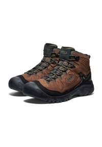 Een paar bruin en zwart hoge wandelschoenen met stevige zolen en vetersluiting op een witte achtergrond.