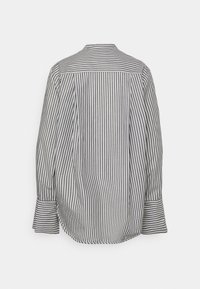 Chemise à manches longues à rayures verticales noires et blanches, avec de larges poignets et un empiècement sur le haut du dos, vue de dos.