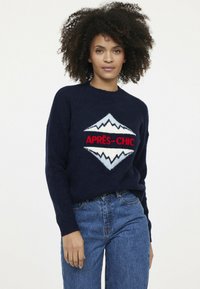 Dunkelblauer Strickpullover mit dem Text "APRÈS-CHIC" und einer Berggrafik in Weiß und Rot, mit Rundhalsausschnitt und lässiger Passform.