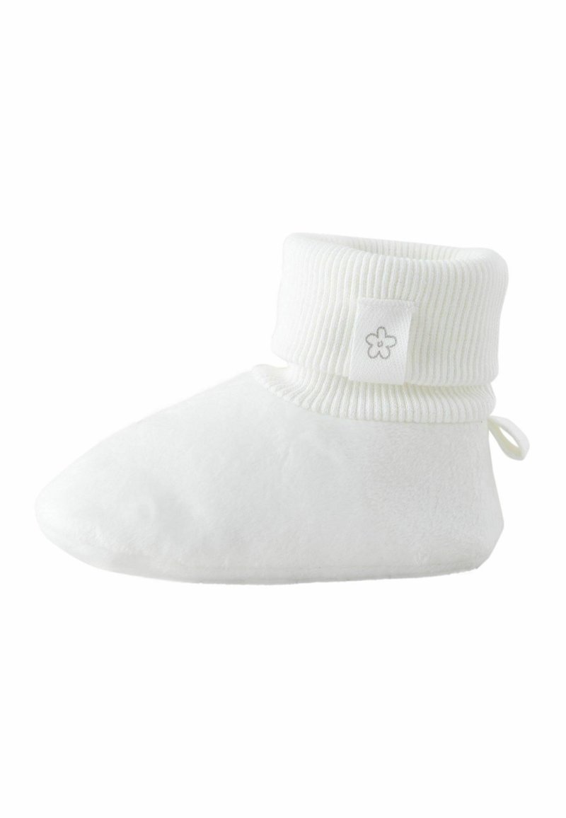 Chausson en polaire blanche avec un revers côtelé. Présente une petite étiquette avec un logo de fleur. Texture douce et confortable, conçue pour la chaleur et le confort.