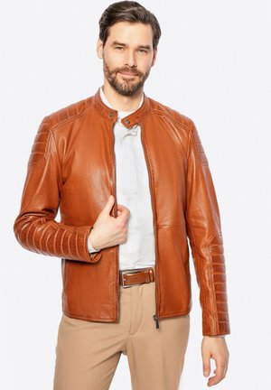 Giacca in pelle marrone con colletto rialzato, dettagli trapuntati sulle spalle e chiusura con zip. Texture liscia e design aderente.