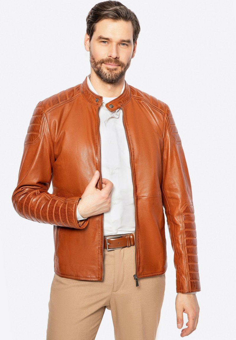 Braune Lederjacke mit Stehkragen, gesteppten Schulterakzenten und einem Reißverschluss vorne. Glatte Textur mit taillierter Passform.