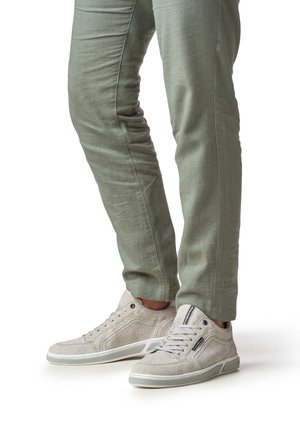 Zapatillas deportivas gris claro con parte superior de tela texturizada, punta redondeada y suela blanca contrastante. Combinadas con pantalones verdes de corte ajustado.