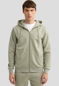 Hellgrüner Reißverschluss-Hoodie aus weichem Material, mit einem Frontreißverschluss, Taschen, verstellbarem Kordelzug und Logo-Detail.
