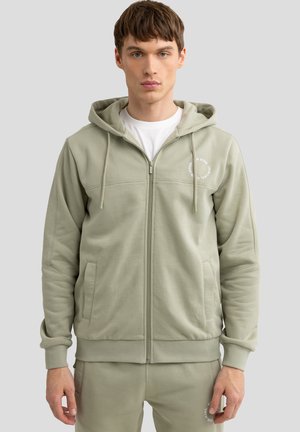 Light green zip-up hoodie made of soft fabric, featuring a front zipper, pockets, adjustable drawstring hood, and logo detail.