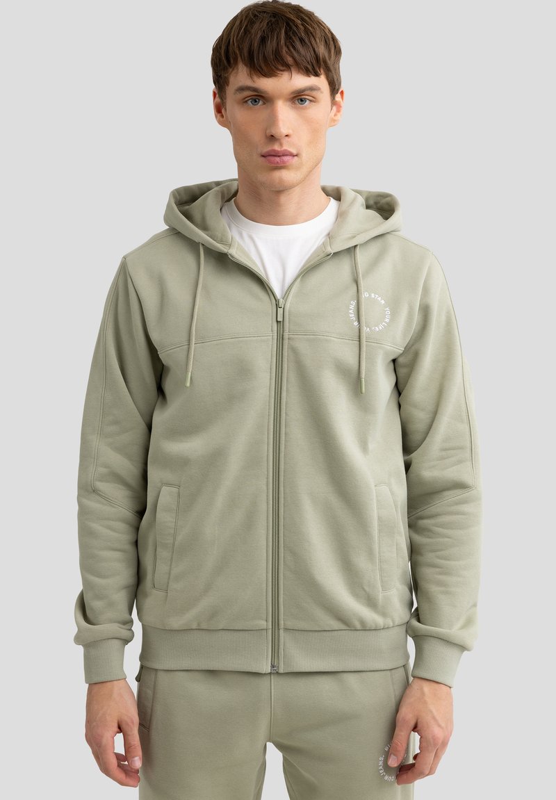 Hellgrüner Reißverschluss-Hoodie aus weichem Material, mit einem Frontreißverschluss, Taschen, verstellbarem Kordelzug und Logo-Detail.