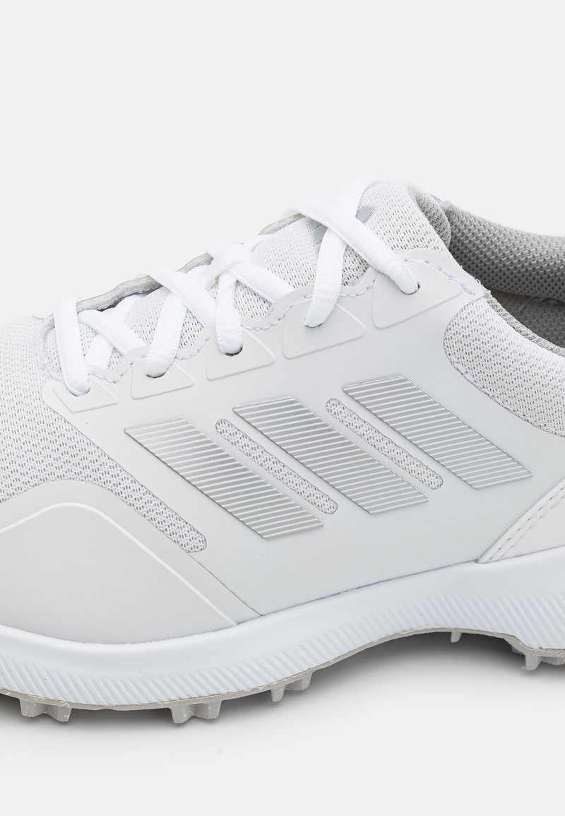 Weiße Sportchuhe mit einem strukturierten Mesh-Obermaterial, kantigen Designelementen und einer Gummisohle mit kleinen Stollen für besseren Halt.