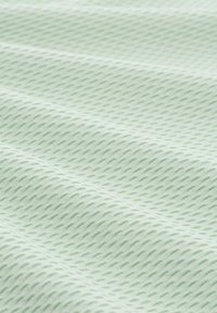 Getextureerde stof in licht muntgroen, met een diamantvormig patroon en verhoogde ribbels, die visuele diepte en zachtheid creëren.