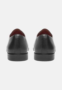 Zwarte leren schoenen met een strak ontwerp, ronde neus en een gladde textuur. De achterkant heeft minimale stiksels en een lage hak. Het interieur is rood.