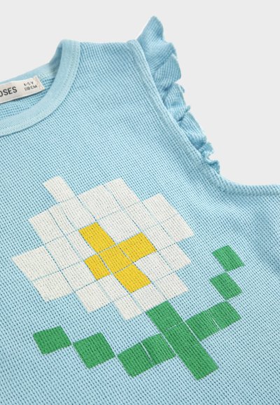 Lyseblå strikket børnetop uden ærmer med pixeleret design af en hvid og gul blomst med grøn stilk samt flæsekant ved skulderen.