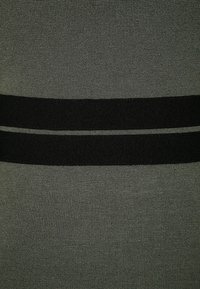 Virkat tyg topp i mörkgrön med svarta horisontella ränder. Texturerad yta, kroppsnära form och inga synliga detaljer eller dekorationer.