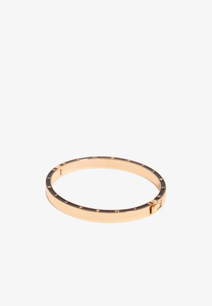 Złota bransoletka z czarną emalią cienko wtopioną oraz wygrawerowanymi literami wokół zewnętrznego brzegu, pokazana na białym tle.