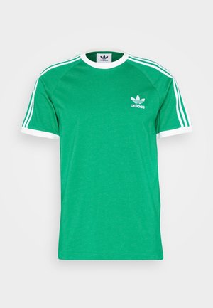 Grünes Adidas Kurzarmshirt mit weißem Rand am Kragen und an den Ärmeln, mit drei weißen Streifen auf den Schultern und Adidas-Logo auf der Brust.