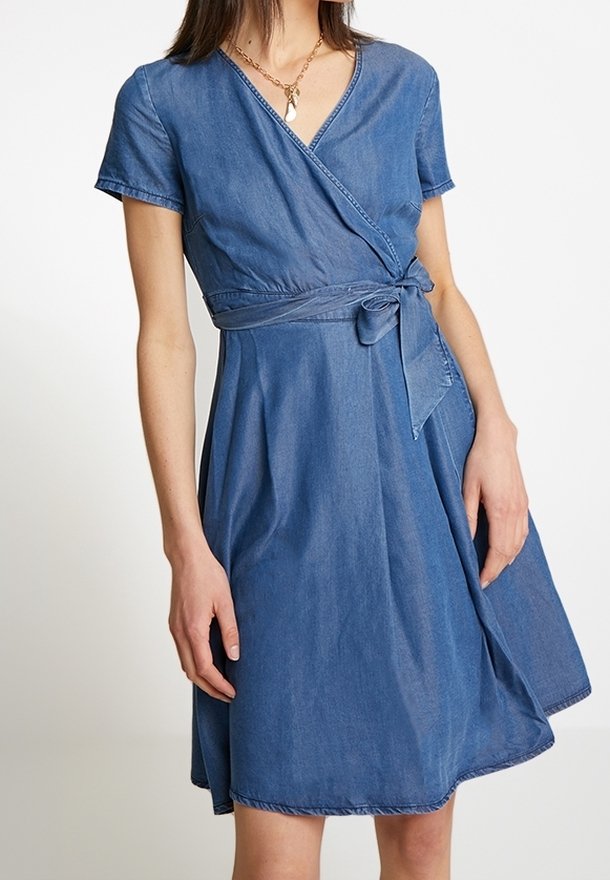 Denim wrap-dress, jossa on lyhyet hihat, vyötärösolmu ja flare-hame. Sininen väri, jossa on sileä tekstuuri ja hienovaraiset ompeluyksityiskohdat.