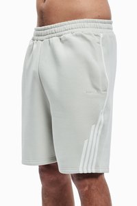 Lys grå joggebukser med elastisk midje, sidelommer og hvite tre-stripes detaljer langs venstre ben. Glatt tekstur.