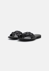 Svarta slip-on sandaler med flätade remmar som pryds av silverstift, platt sula och en minimalistisk design. Slät yta och lätt konstruktion.