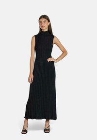 Abito maxi senza maniche in maglia nera con collo alto, texture a costine e corpino aderente, che mette in risalto una gonna svasata.