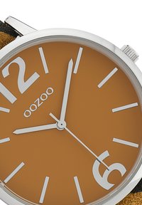 Round wristwatch with a brown dial, white hour markers, and silver hands. Brand name "oozoo" is displayed below the 12 o'clock mark.