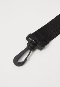 Correa de nylon negra con superficie texturizada, que presenta un clip y un gancho de plástico para un ajuste seguro. Sin patrones o acentos adicionales.