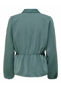 Blouse verte à la texture douce, manches longues et taille cintrée. Dotée d'un col classique et d'un motif côtelé subtil.