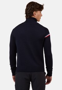 Maglione lavorato a maglia blu navy con colletto alto a costine, caratterizzato da una striscia di accento rossa, bianca e blu sulla spalla e polsini e orlo aderenti.