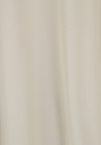 Tissu beige avec une texture tissée subtile et de doux plis verticaux créant des ombres délicates.