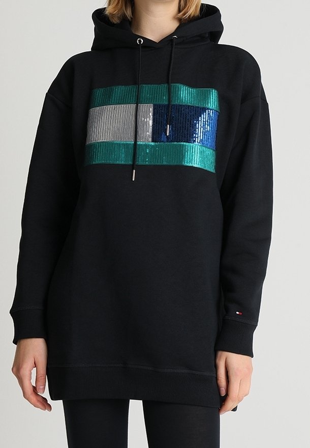 Czarna bluza z kapturem z frontalnym wzorem z cekinów, zawierającym niebieskie, zielone, srebrne i szare paski. Regulowany sznurek i ściągacze przy mankietach.