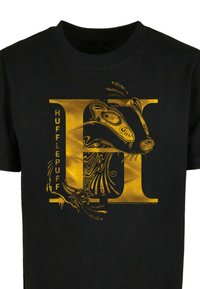 Melna T-kreklu ar lielu zeltītu grafiku ar burtu "H", kurā ir detalizēts lūša dizains un vārds "HUFFLEPUFF" vertikālā izkārtojumā.