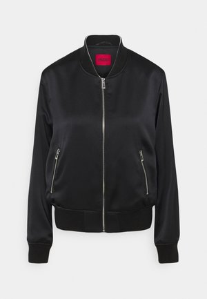 Veste bomber noire avec col, poignets et ourlet côtelés, fermeture éclair argentée à l'avant, deux poches latérales zippées et étiquette de marque rouge à l'intérieur du col.