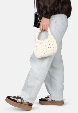 Mini borsa intrecciata bianca con un motivo testurizzato e due manici corti, abbinata a jeans light blue e sneakers nere con suola platform.