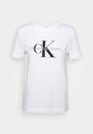 Vit bomulls t-shirt med korta ärmar, som har en stor svart "CK"-logotyp och texten "Calvin Klein Jeans" nedanför i grå.