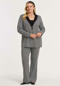 Sorte og hvide houndstooth-mønstrede jakkes�æt med en skræddersyet blazer med notch-lapel og flade bukser. Glat stof.