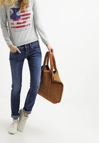 Brun läderhandväska med robusta dubbla handtag, mjuk textur och rektangulär form. Grå sweatshirt med en design av en röd och blå flagga.