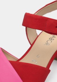 Γυναικεία σανδάλι σε κόκκινο και ροζ με λουράκι στον αστράγαλο και μπεζ πάτο που δείχνει μέγεθος 4½ και το όνομα της μάρκας.