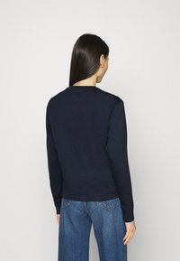 Lahti pitkähihaine paita, jossa on pyöreä kaulus ja rento istuvuus, valmistettu pehmeästä puuvillamateriaalista. Vähäiset ompeluyksityiskohdat harteilla jahelmassa.