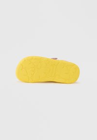 Κίτρινη σόλα από καουτσούκ παπουτσιού με υφή που απεικονίζει σχήματα που μοιάζουν με φύλλα και μια περιορισμένη σήμανση. Επίπεδο και στρογγυλεμένο σχέδιο.