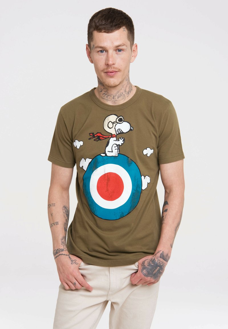 Olivenfarbiges Baumwoll-T-Shirt mit einem Cartoon-Hund, der eine Brille und einen Schal trägt, sitzt auf einem blauen und roten Ziel-Design, umgeben von weißen Wolken.