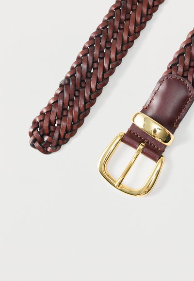 Πλεχτή καφέ δερμάτινη ζώνη με γυαλιστερή χρυσή μεταλλική αγκράφα σε λευκό φόντο.