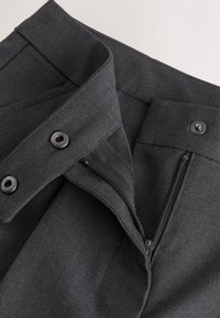 Dunkelgraue Hose mit offenem Reißverschluss, geknöpftem Bund und sichtbaren Reißverschluss- und Druckknopfdetails.