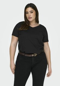T-shirt noir à manches courtes avec un col en V, porté avec un jean en denim foncé et une ceinture marron avec une boucle circulaire en or.