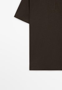 Ciemnobrązowa, krótkorękawowa koszulka polo z kołnierzykiem i suwakiem do połowy długości, pokazana na płasko na białym tle.